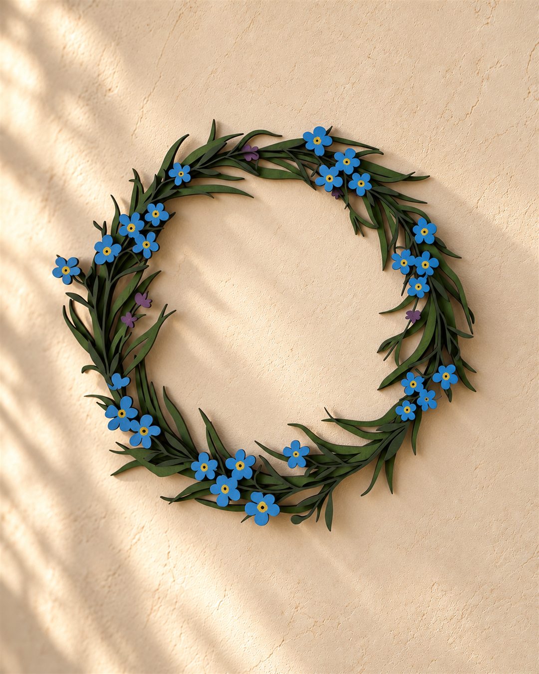 A circular wooden wreath with small rounded blue flowers and slender green leaves on a warm plaster wall