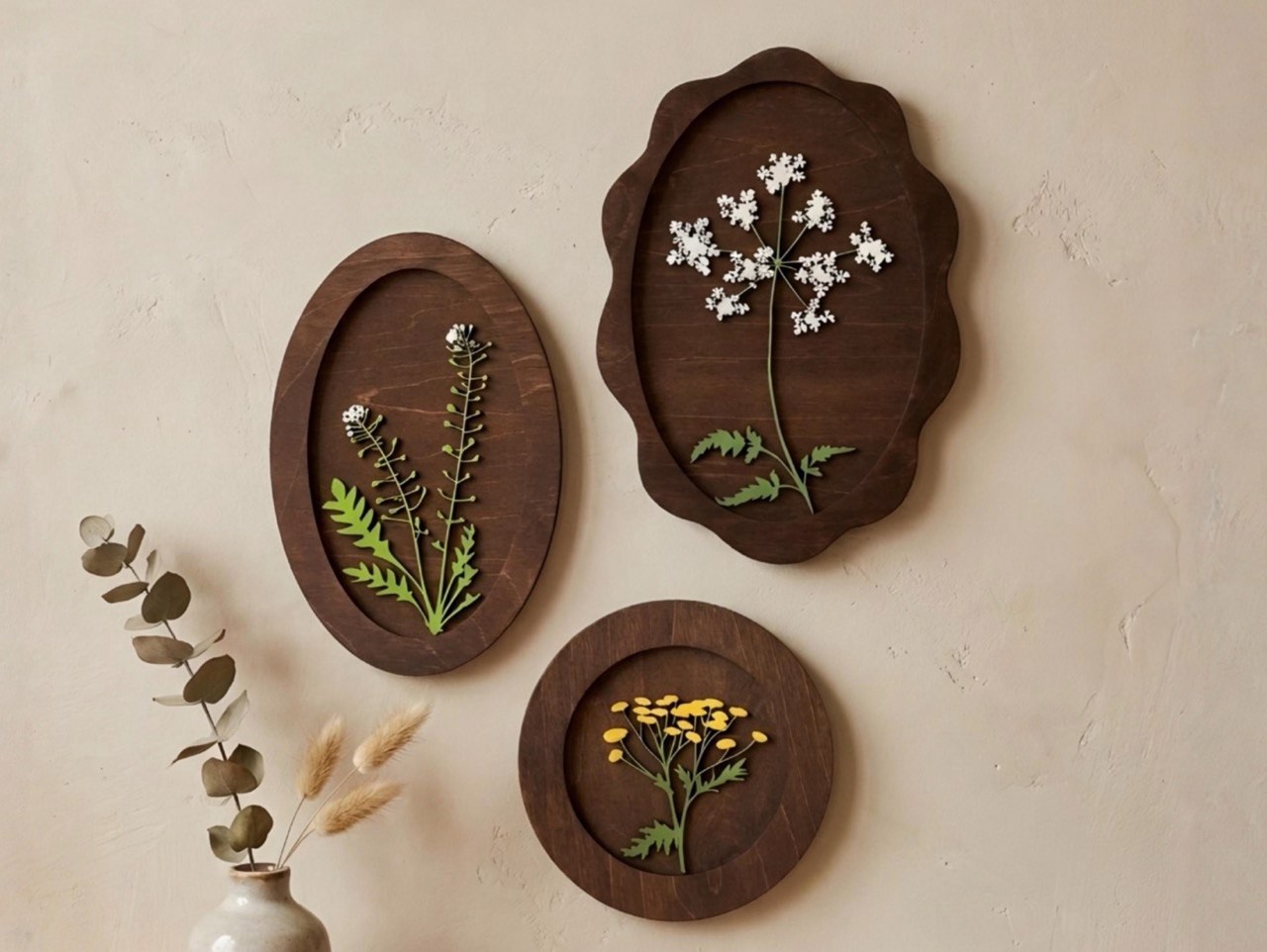 Three dark wood panels with delicate botanical forms on a pale plaster wall