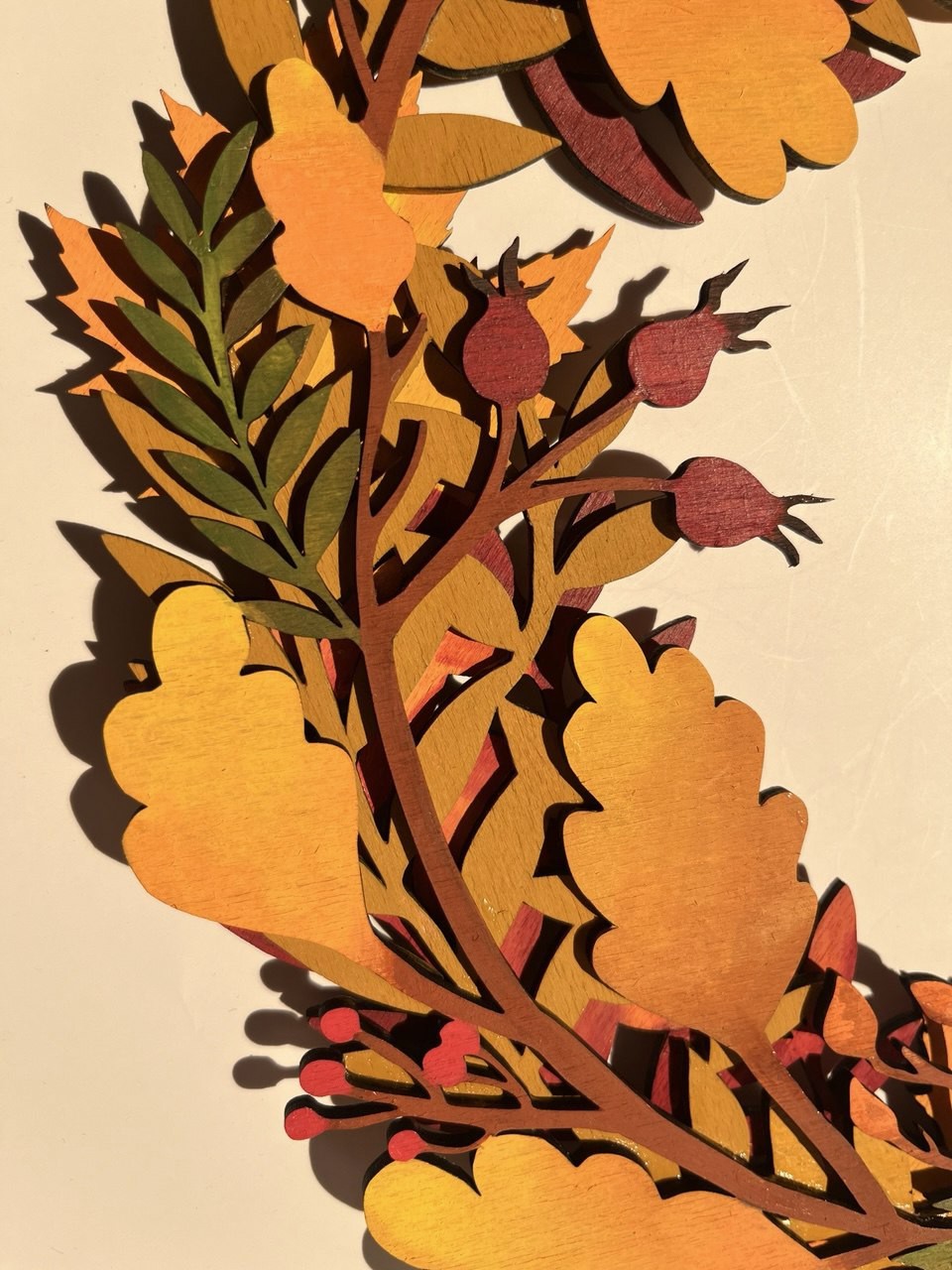 Close view of painted wooden oak leaves and berries showing their layered edges and grain